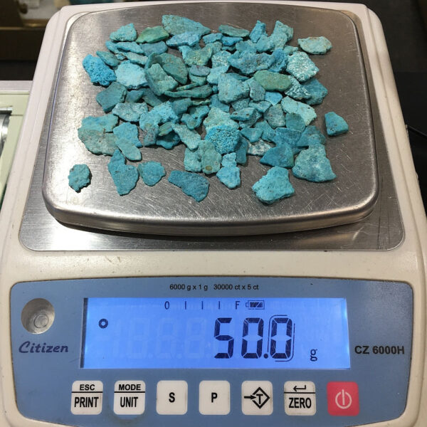 A pile of bright blue Turquoise chips on a scale. Combined weight is 50 grams.