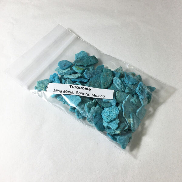 A clear plastic bag filled with chips of Turquoise with a label that says "Turquoise, Mina Maria, Sonora, Mexico". Material is suitable for inlay.