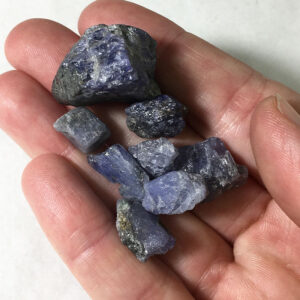 Eight small pieces of Tanzanite rough rock in the palm of a hand