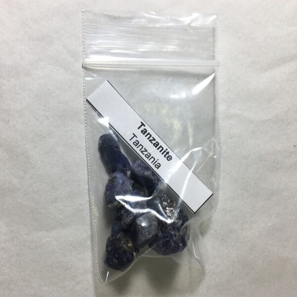 Eight small pieces of Tanzanite rough rock in a clear bag with a label that says "Tanzanite, Tanzania"