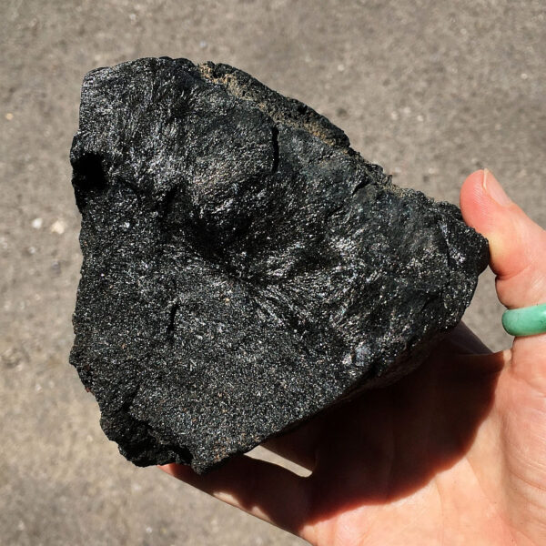 3.08 pound piece of Velvet Black Tourmaline rough rock pictured in sunlight. Side two of six sides.