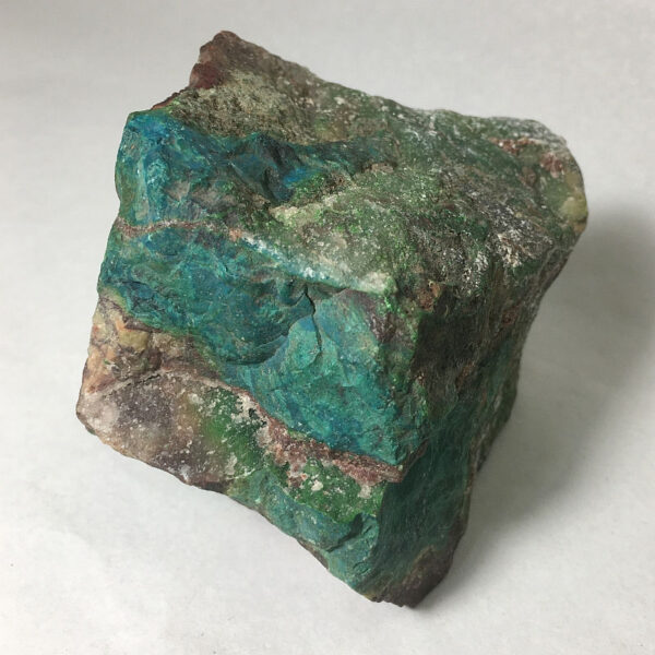 1.02 pound piece of Silicated Parrot Wing Chrysocolla rough rock, pictured dry on a white background