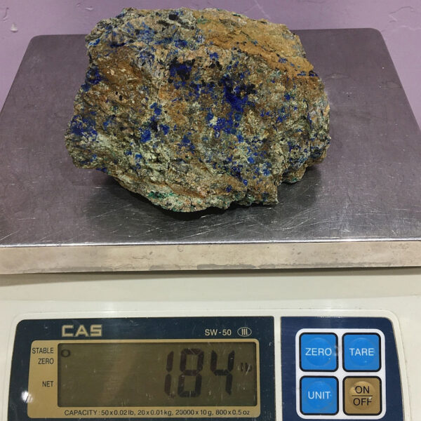 A piece of Spotted Azurite rough rock pictured on a scale. Piece weighs 1.84 pounds.