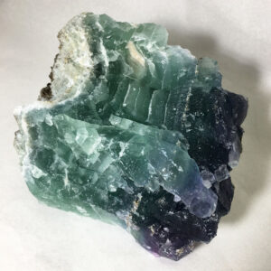 3.58 pound piece of Fluorite rough rock pictured dry on a white seamless background. Rock is mostly green with some purple and blue.