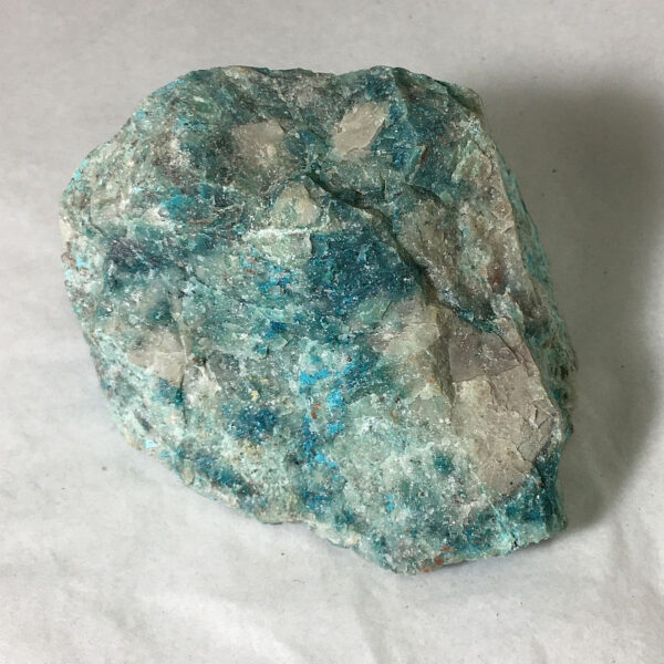 0.70 pound piece of Teal Turq Rhyolite rough rock, pictured dry on a white background