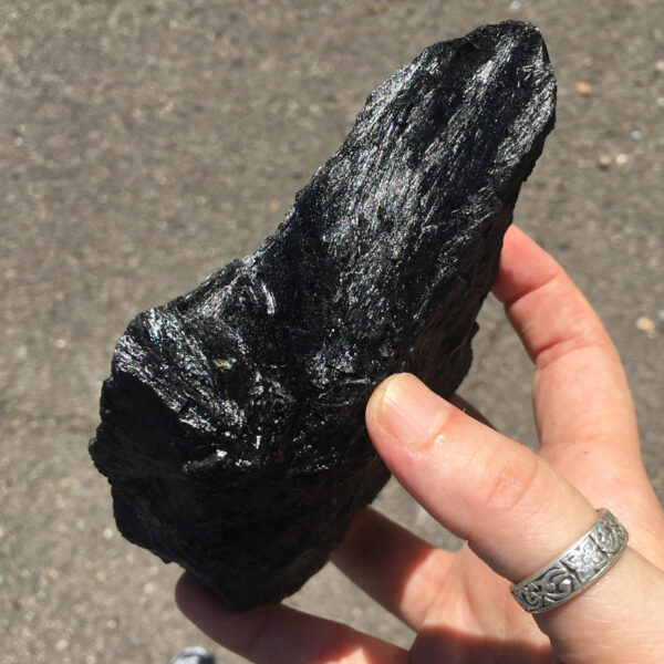 1.56 pound piece of Velvet Black Tourmaline rough rock, pictured dry in sunlight. Side two of six sides.