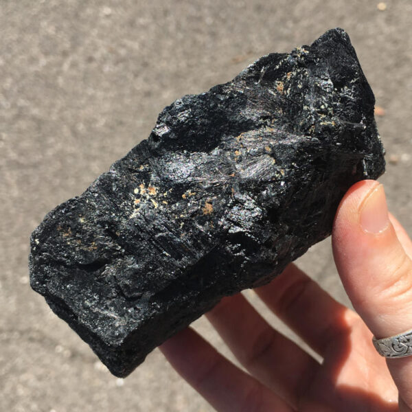 1.56 pound piece of Velvet Black Tourmaline rough rock, pictured dry in sunlight. Side four of six sides.