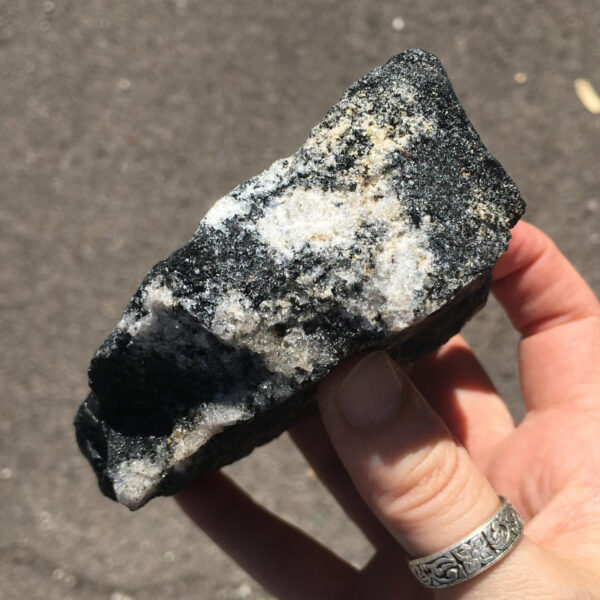 1.56 pound piece of Velvet Black Tourmaline rough rock, pictured dry in sunlight. Side five of six sides.