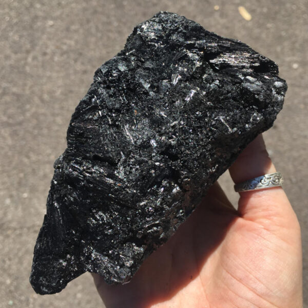 1.70 pound piece of Velvet Black Tourmaline rough rock, pictured dry in sunlight. Side four of five sides.