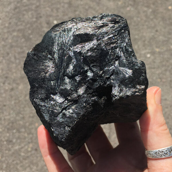 1.80 pound piece of Velvet Black Tourmaline rough rock, pictured dry in the sunlight. Side one of six sides.