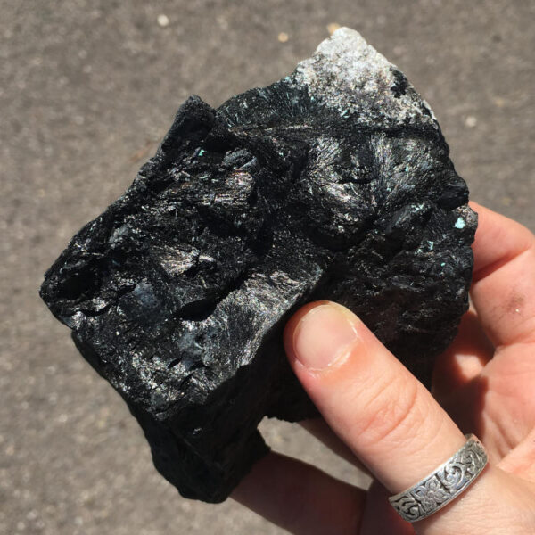 1.80 pound piece of Velvet Black Tourmaline rough rock, pictured dry in the sunlight. Side two of six sides.