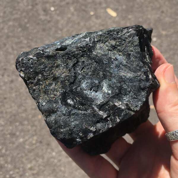 1.80 pound piece of Velvet Black Tourmaline rough rock, pictured dry in the sunlight. Side three of six sides.