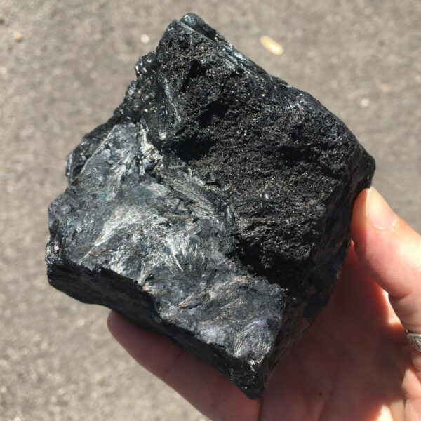 1.80 pound piece of Velvet Black Tourmaline rough rock, pictured dry in the sunlight. Side four of six sides.