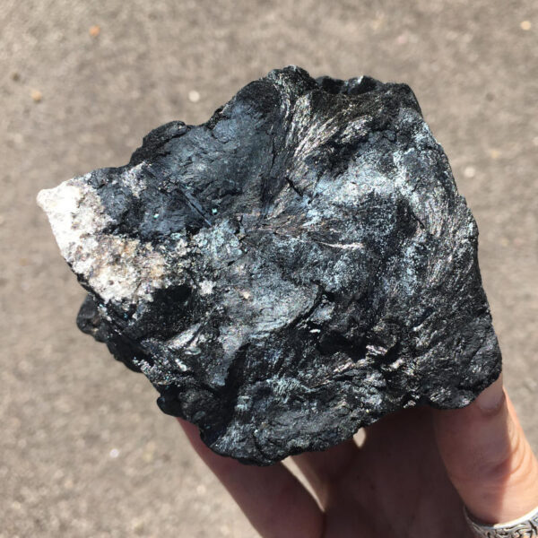 1.80 pound piece of Velvet Black Tourmaline rough rock, pictured dry in the sunlight. Side five of six sides.