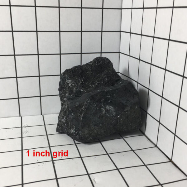 1.80 pound piece of Velvet Black Tourmaline rough rock pictured on a one inch grid. Piece measures approximately 3.5 by 3 by 3 inches