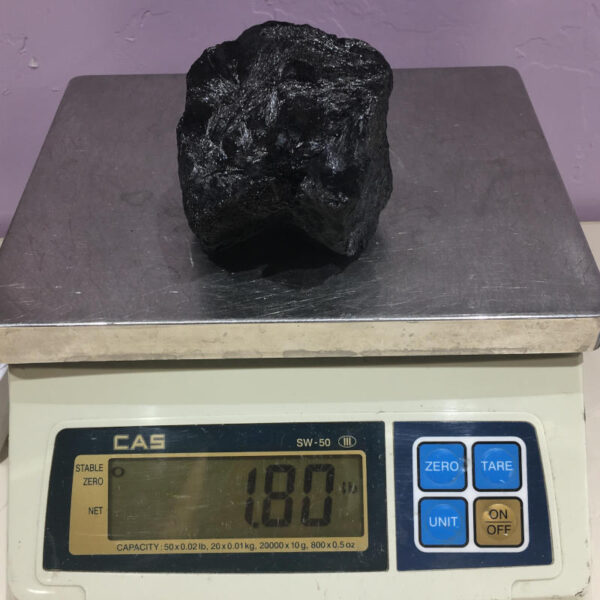 A piece of Velvet Black Tourmaline rough rock pictured on a scale. Piece weighs 1.80 pounds.