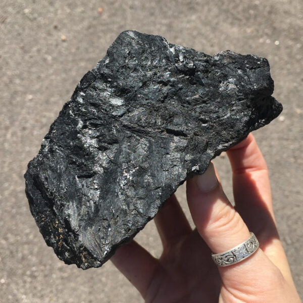 2.04 pound piece of Velvet Black Tourmaline rough rock, pictured dry in the sunlight. Side five of six sides.