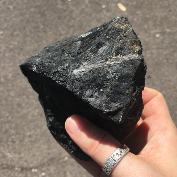 2.04 pound piece of Velvet Black Tourmaline rough rock, pictured dry in the sunlight. Side six of six sides.