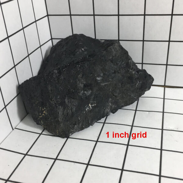 2.04 pound piece of Velvet Black Tourmaline rough rock pictured on a one inch grid. Piece measures approximately 4.5 by 4 by 2.25 inches