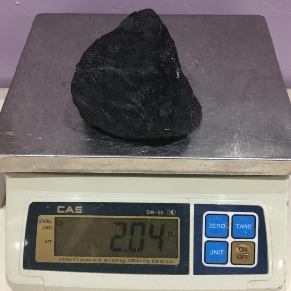 A piece of Velvet Black Tourmaline rough rock, pictured dry on a scale. Piece weighs 2.04 pounds.