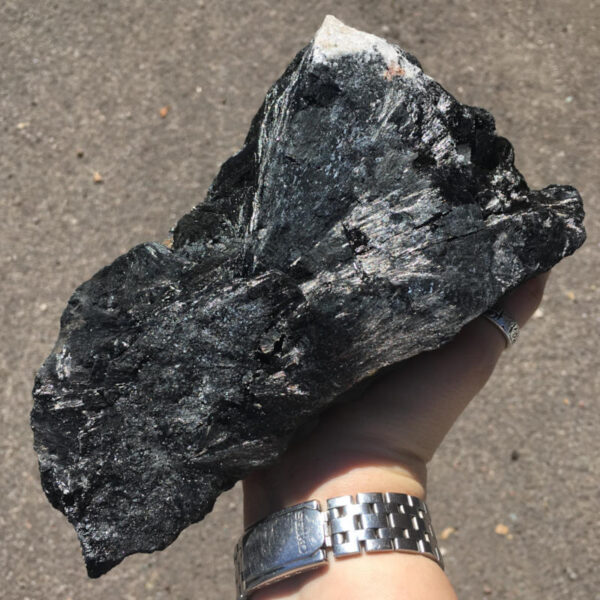 5.22 pound piece of Velvet Black Tourmaline rough rock, pictured dry in the sunlight. Side three of six sides.