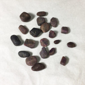 20 small raw ruby (corundum) pebbles on a white backdrop