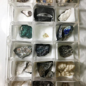 Open plastic specimen box containing 18 mineral specimens.