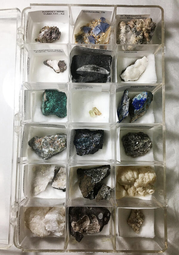 Open plastic specimen box containing 18 mineral specimens.